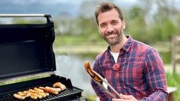  Daniel Aßmann grillt Bratwürste.