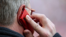 Kopf eines Mannes von hinten, der ein Handy ans Ohr hält