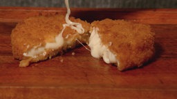 Backcamembert verzeilt auf dem Tisch liegend, Käse läuft heraus.