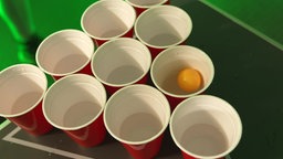 10 Bierpongbecher von oben, in einem schwimmt ein Tischtennisball.