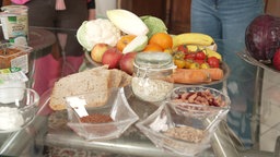 Lebensmittel -- wie Vollkornbrot, Samen, Gemüse, Obst -- auf einem Tisch.