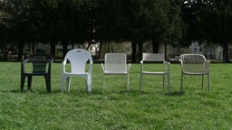 Das Bild zeigt fünf Gartenstühle aus Plastik.