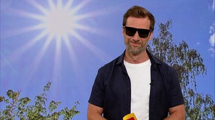 Daniel Aßmann steht im Servicezeit-STudio. Er trägt eine Sonnenbrille.
