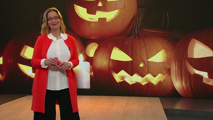 Yvonne Willicks steht im Servicezeit-Studio. Im Hintergrund sieht man Halloween-Kürbisse.