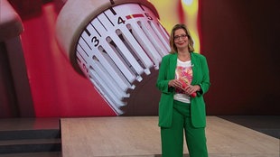  Yvonne Willicks steht im Servicezeit-Studio. Im Hintergrund sieht man die Nahaufnahme eines Heizreglers.