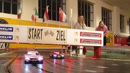 Das Bild zeigt zwei Frauen bei einem Autorennen.