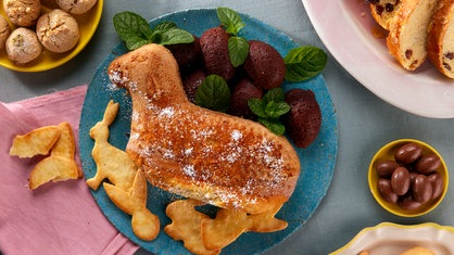 Das Bild zeigt ein Osterkörbchen mit einem Huhn, Eiern und kleinen Hasen.