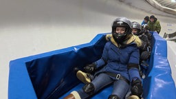 Das Bild zeigt eine Frau mit Helm in einem Go-Kart.