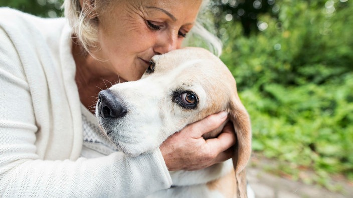 Eine Frau knuddelt einen Hund mit hellem Fell 