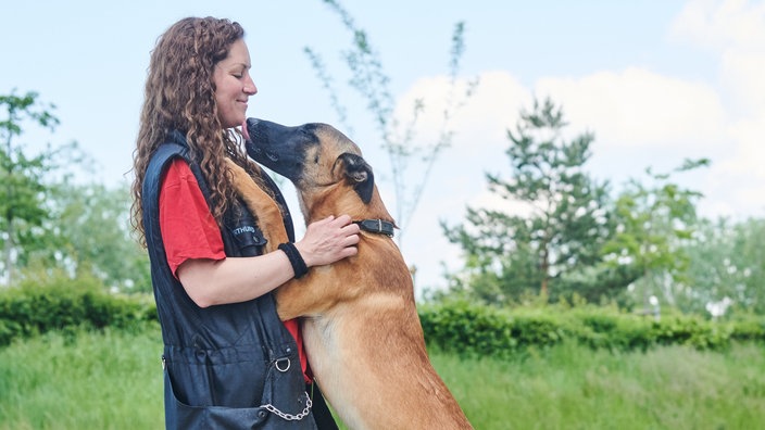 Ein Schäferhund schleckt eine Frau ab 