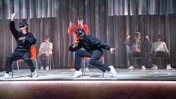 Maskierte Menschen auf Theaterbühne