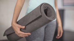 Frau mit einer Yogamatte in der Hand