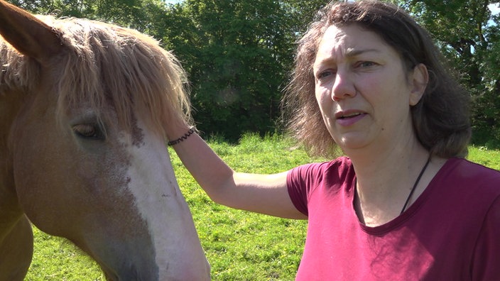 Katrin Reuter streichelt ein Pferd am Kopf