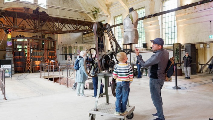 Mann steht mit Kind vor kinetischem Kunstwerk