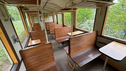 Alter Wagon mit Holzbänken und Gepäckablage.