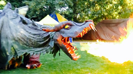 Lebensgroße Drachenpuppe reißt Maul auf und speit Feuer