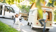 Mann und Frau vor neuem Wohnmobil und Retro-Bully