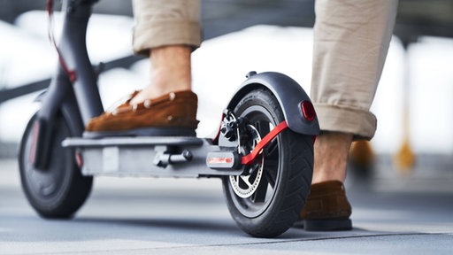 Das Bild zeigt einen Mann auf einem E-Scooter.