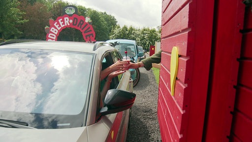 Ein Erdbeershake wird aus der Hütte des Drive In in ein Auto gereicht