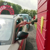 Ein Erdbeershake wird aus der Hütte des Drive In in ein Auto gereicht