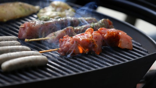 Unterschiedliche Arten Fleisch liegen auf einem Grill