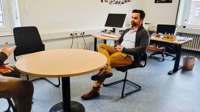 Ein Mann sitzt in einem Büro an einem runden Tisch