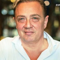 Santo Sabatino, ein brünetter Mann mit Seitenscheitel, glattem Gesicht und blauen Augen, schaut in die Kamera und lächelt.