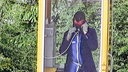 Einer der Täter telefoniert maskiert in einer Telefonzelle.