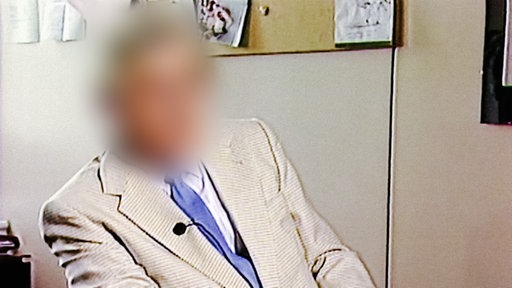 Werner S. sitzt in einem Büro. Sein gesicht ist unkenntlich gemacht.