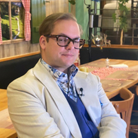 Der ehemalige Neonazi Axel Reitz sitzt auf einem Stuhl in einer Gastronomie