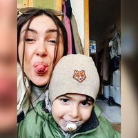 Derya trägt einen Sonnenbrille auf dem Kopf und ihr Sohn Kian eine graue Mütze mit einem Fuchs drauf. Die beiden machen ein Selfie. Derya streckt ihre Zunge heraus und Kian lächelt mit Schnuller im Mund.