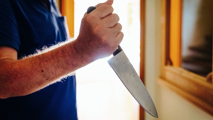 Ein Mann hält ein großes Messer in der Hand
