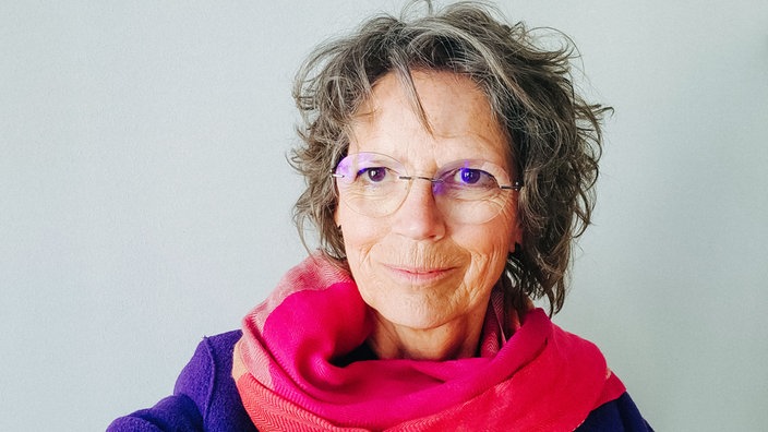 Ein Portraitfoto von Frauenberaterin Luzia Kleene. Sie trägt eine Brille und einen pinken Schal.