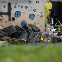 Eine Person liegt in einem Schlafsack auf einem Bürgersteig