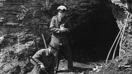 Schwarz-Weiß Aufnahme von Ermittlern vor dem Bunker in Velbert.