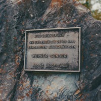 Auf einer Plakette auf dem Gedenkstein steht "Zur Erinnerung an unseren am 25.06.1995 ermordeten Jagdkameraden Werner Senger, seine Jagdfreunde"