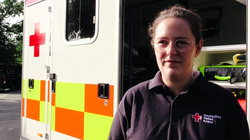 Anna Lena Huckestein in einem dunkelblauen Polohemd vor einem Krankenwagen.