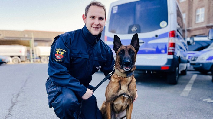 Gregor Köpp kniet neben dem sitzenden Spürhund Cash.