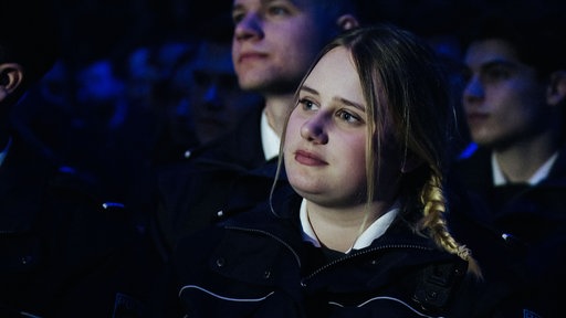 Lucie Piwek sitzt zwischen weiteren Auszubildenden. Sie schaut geradeaus.
