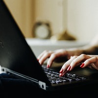 Hände, die auf der Tastatur eines Laptops tippen.