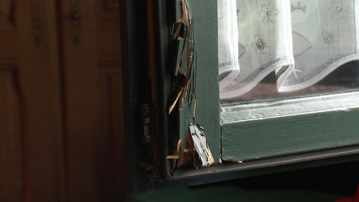 An einem grün gestrichenen Fensterrahmen sind mehrere Absplitterungen infolge eines Einbruchsversuchs zu sehen