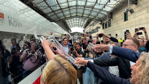 Mehere Menschen schütten ein Glas Wasser auf den ICE.
