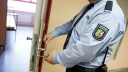 Ein Justizvollzugsbeamter schließt in der Justizvollzugsanstalt eine Tür