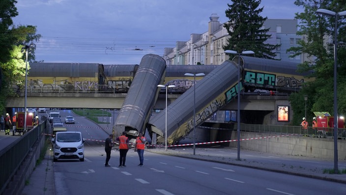 Zwei Waggons eines Güterzugs liegen auf einer Straße, nachdem sie von einer Brücke gestürzt sind