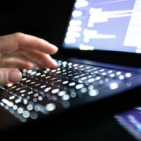 Eine Person tippt mit den Fingern auf einer beleuchteten Laptop-Tastatur