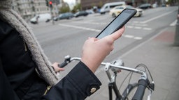 Eine Frau nutzt ihr Smartphone, während sie mit dem Fahrrad fährt
