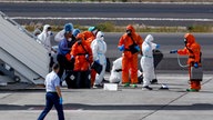 Passagiere der MV Hondius werden am Flughafen von Teneriffa in Schutzanzügen desinfiziert 