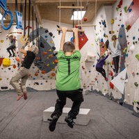 Kinder in der Kletterhalle schwingen an der Sprossenleiter und bouldern in der Wand