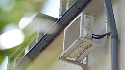 Eine Klimaanlage hängt an der Hauswand eines Mehrfamilienhauses