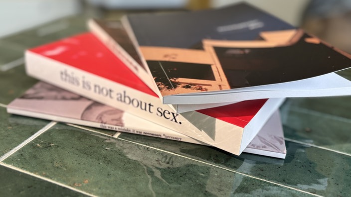 Vier unterschiedliche Bücher liegen auf einem Stapel auf einem Tisch